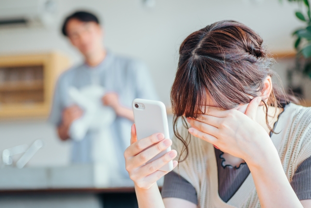 スマホを見て落ち込む女性